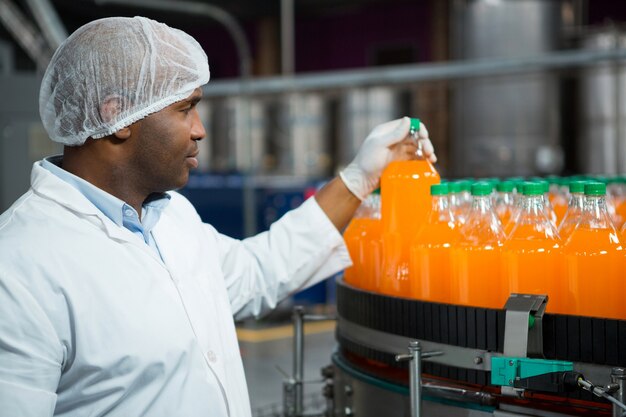 Free Photo male worker checking juice bottles in factory