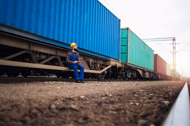 Free Photo male worker checking train trailers with shipping containers before departure