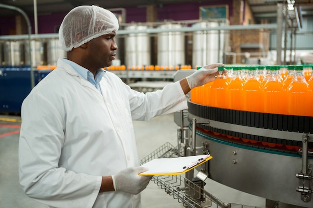 Free Photo male worker examining bottles in juice factory