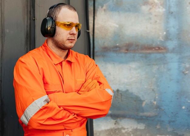 Free photo male worker in uniform with protective glasses and headphones