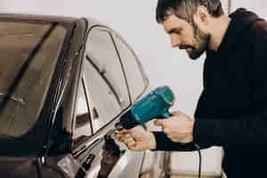 Free photo male worker wrapping car with ptotective foil