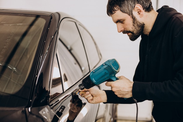 Free Photo male worker wrapping car with ptotective foil