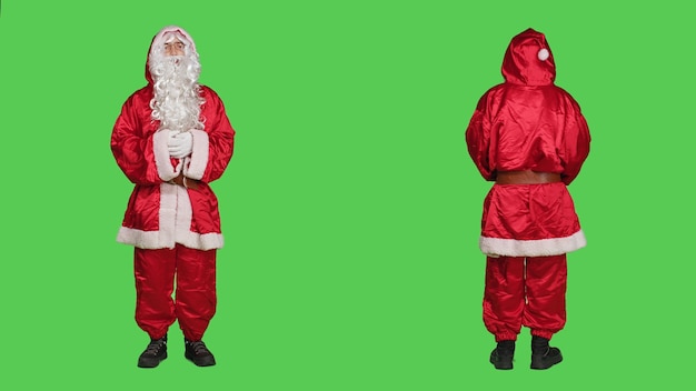 Free Photo man acting like santa in costume saying ho ho ho, portraying december famous character for christmas eve celebration. saint nick with hat and beard standing over full body greenscreen.