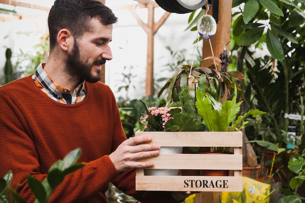 Free photo man admiring plants in box