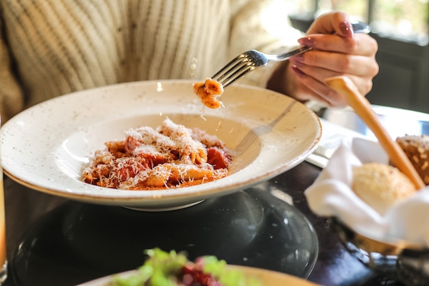 Man are eating penne pasta with tomato sauce parmesan vegetables meat side view