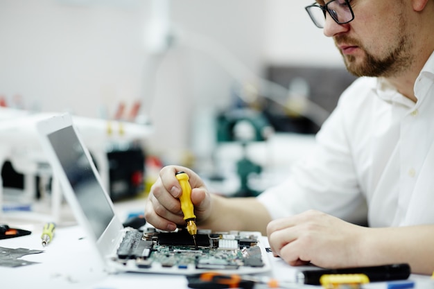 Man Assembling Circuit Board in Laptop