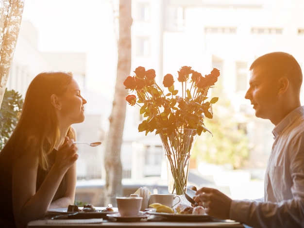 Man and attractive woman at table with desserts and flowers