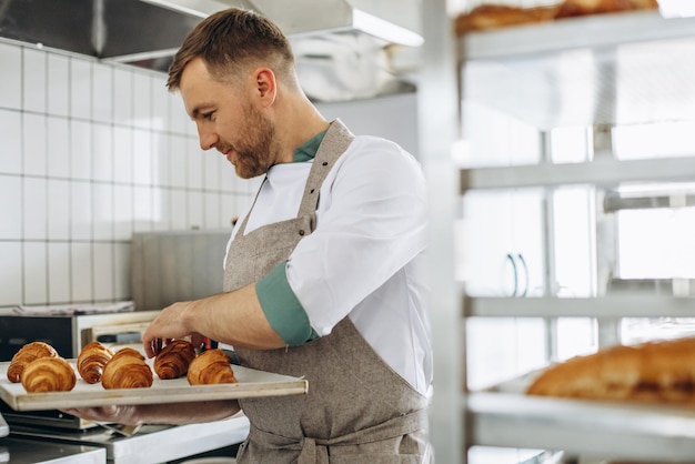 Free Photo man baker holding croissants at the bakehouse