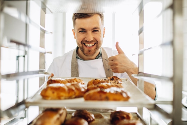 Free photo man baker at the kitchen by the pastry cart