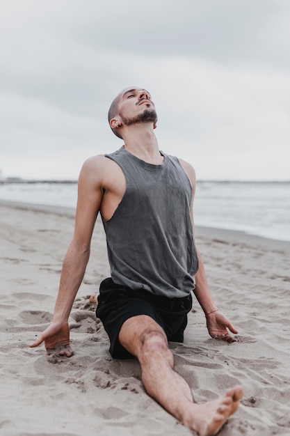 Man on the beach doing the split in yoga routine