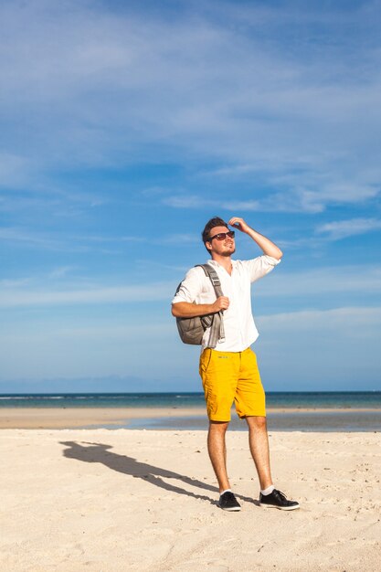 Man on beach smiling and wearing hipster bright outfit