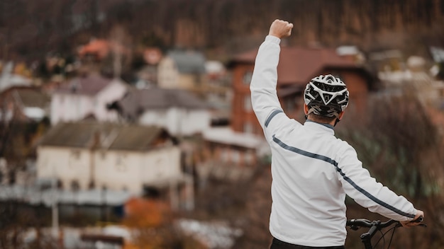 Free photo man being victorious after riding his bike with copy space