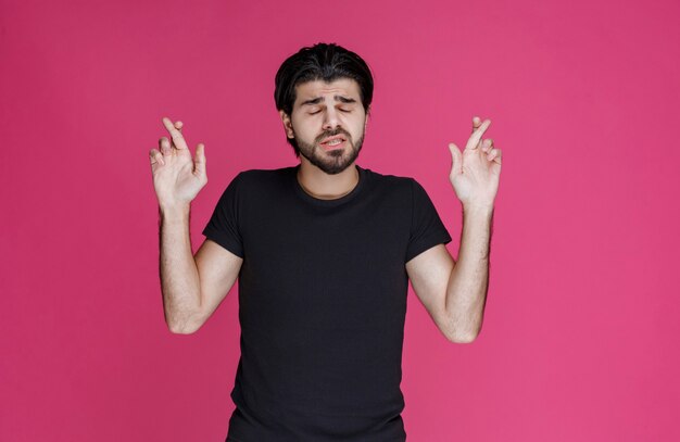 Man in black shirt making hand cross sign