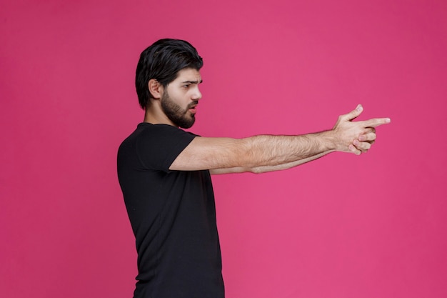 Free Photo man in black shirt making hand gun sign