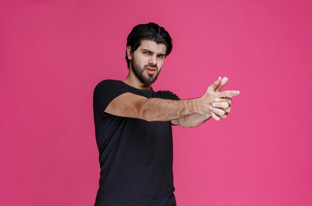 Man in black shirt making hand gun symbol