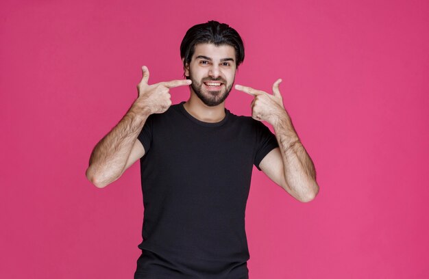 Man in black shirt pointing his mouth and asks smiling