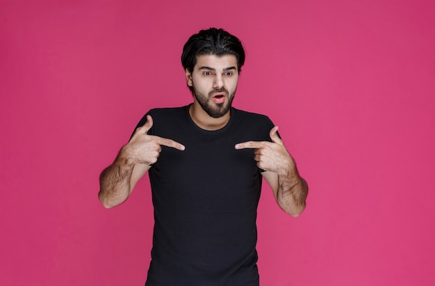 Man in black shirt pointing at something or introducing someone