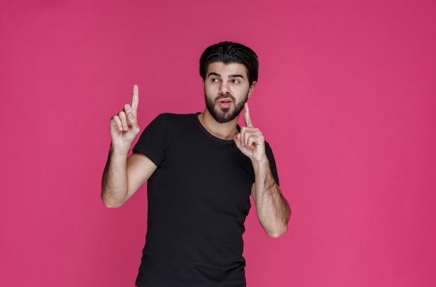 Free Photo man in black shirt pointing at something or introducing someone