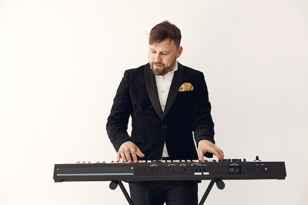 Free photo man in black suit standing with a electro keyboard