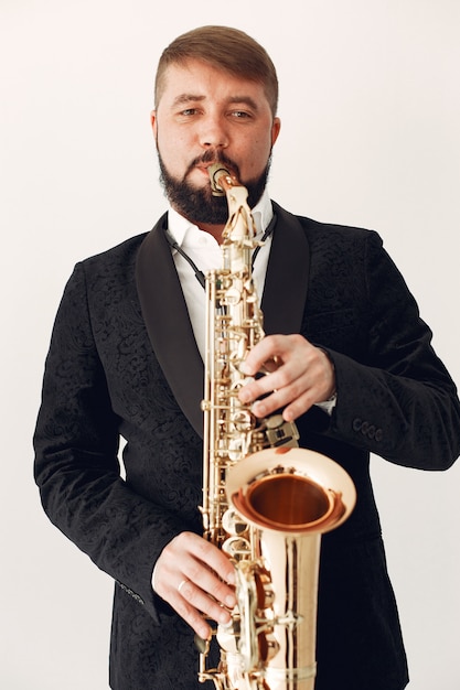 Free Photo man in black suit standing with a saxophone