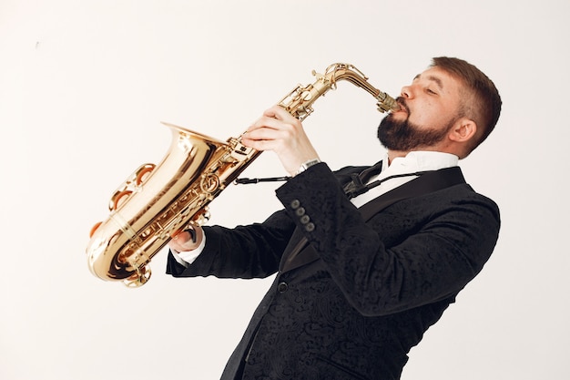 Man in black suit standing with a saxophone