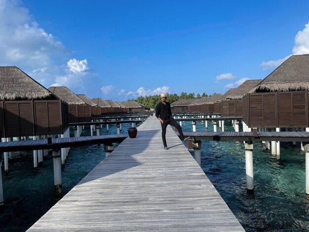 Man in black over a wooden jetty in the Maldives