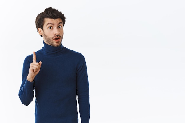 Free photo man in blue high neck sweater raise one finger and sharing his thought, suggest something during office meeting, give advice or recommend product