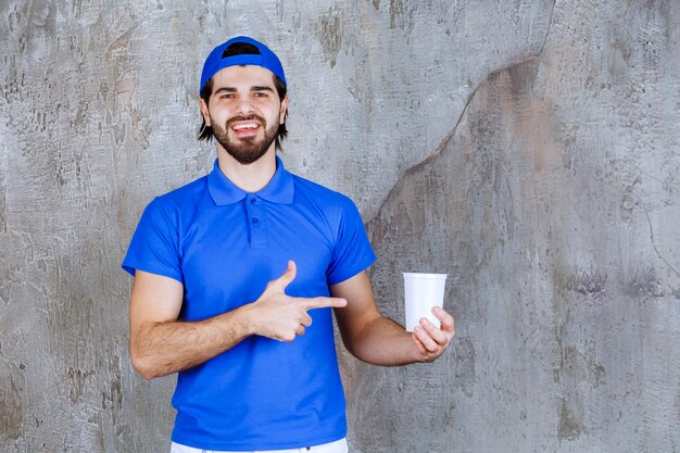 Free photo man in blue uniform holding a takeaway drink