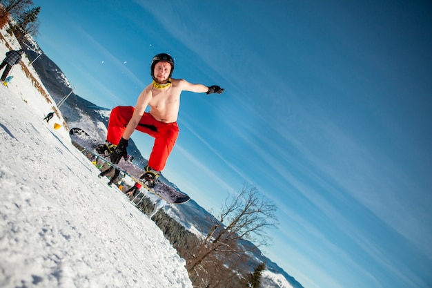 Free photo man boarder jumping on his snowboard against the backdrop of mountains