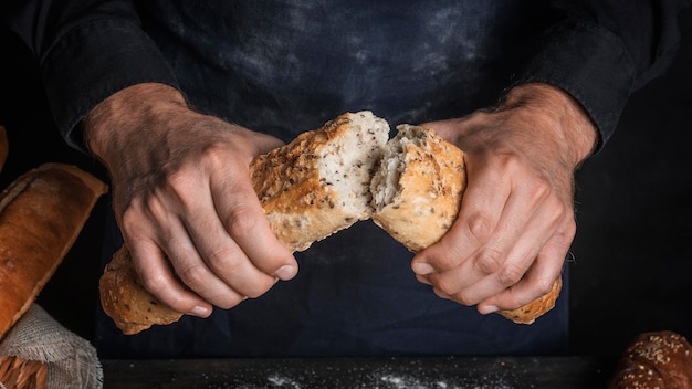 Free photo man breaking a loaf of bread