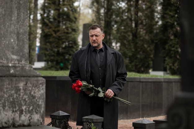 Man bringing roses to a gravestone at the cemetery