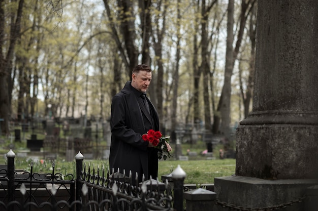 Man bringing roses to a gravestone at the cemetery