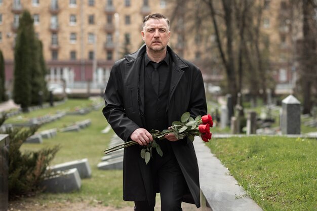 Man bringing roses to a gravestone at the cemetery