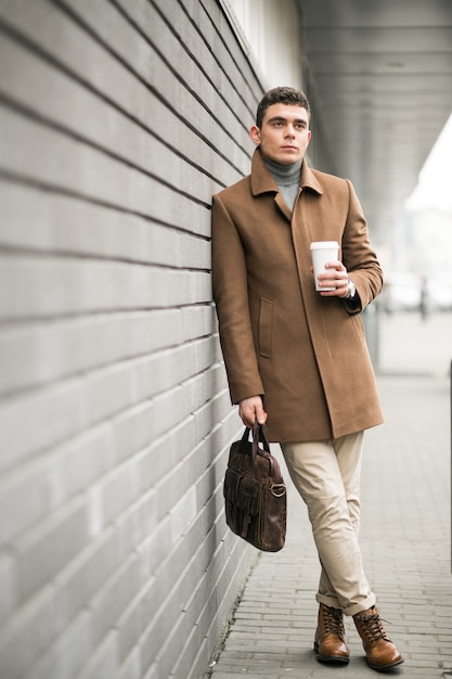 Free photo man in brown coat with coffee