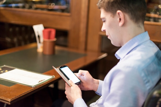 Free photo man browsing smartphone in restaurant