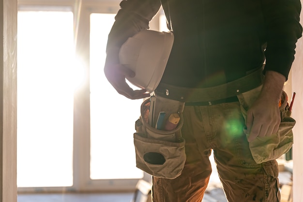 A man builder holds a protective helmet in his hands, part of the body.