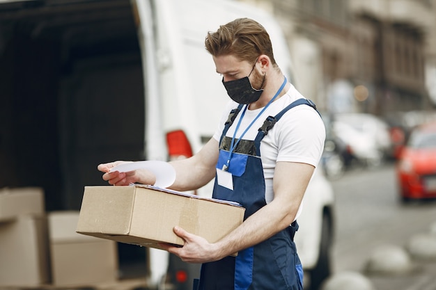 Free photo man by the truck. guy in a delivery uniform. man in a medical mask. coronavirus concept.