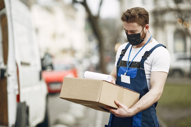 Free photo man by the truck. guy in a delivery uniform. man in a medical mask. coronavirus concept.