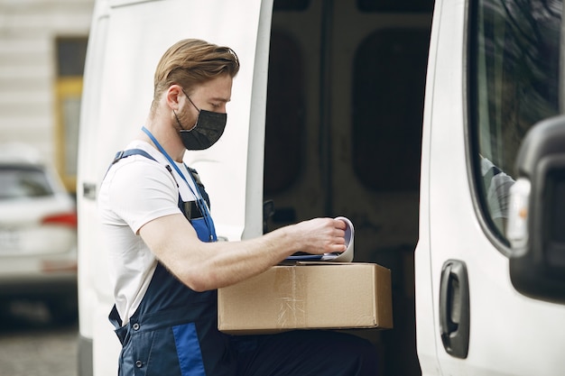 Free photo man by the truck. guy in a delivery uniform. man in a medical mask. coronavirus concept.