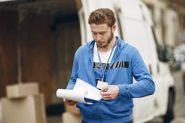 Free Photo man by the truck. guy in a delivery uniform. man with clipboard.