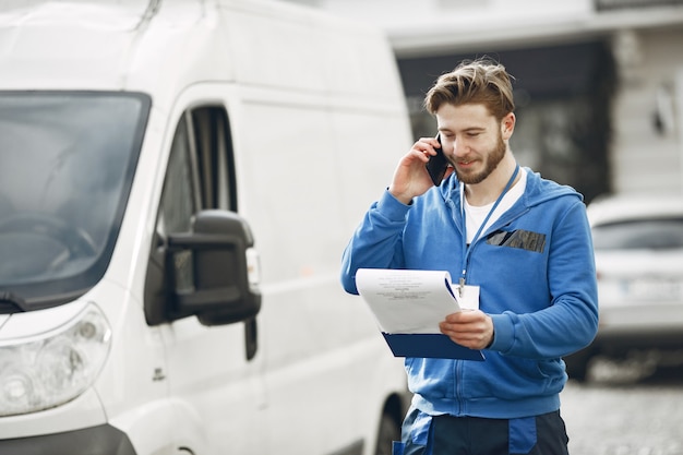 Free photo man by the truck. guy in a delivery uniform. man with clipboard.