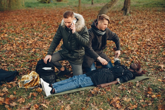 Man calls an ambulance. African girl is lying unconscious. Providing first aid in the park