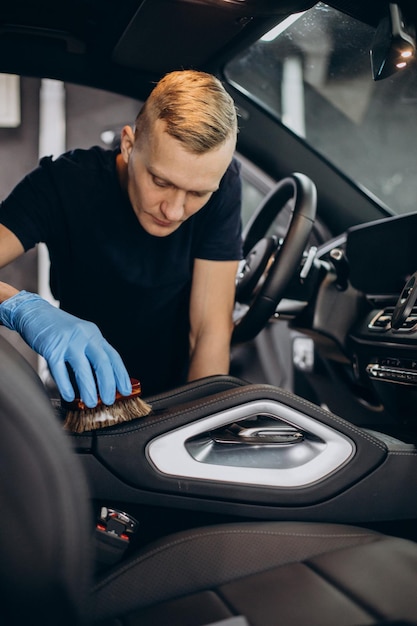 Man at car clean using brush to clean up all details inside the vehicle