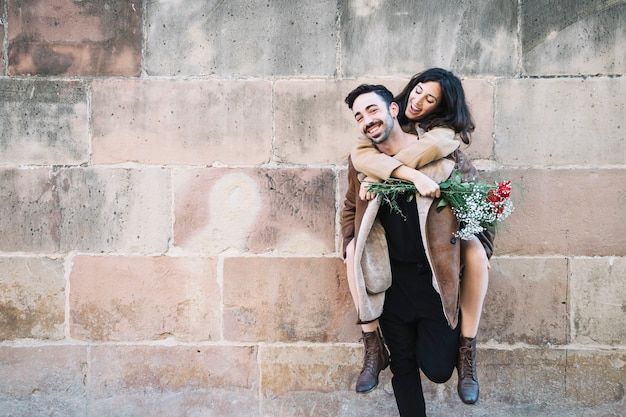 Man carrying woman on back near wall