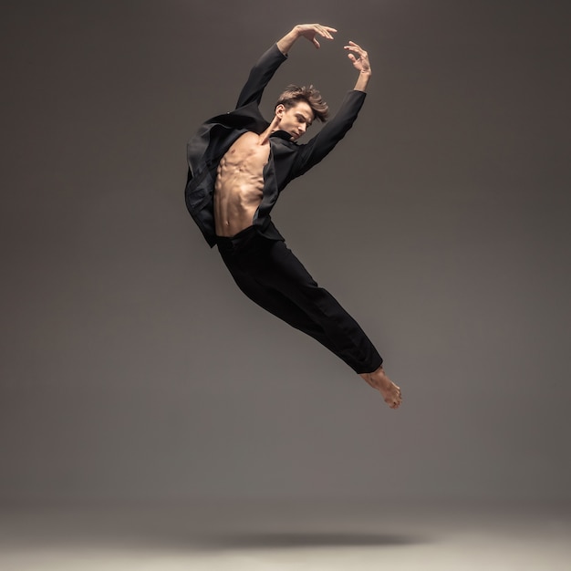 Man in casual office style clothes jumping and dancing isolated on grey