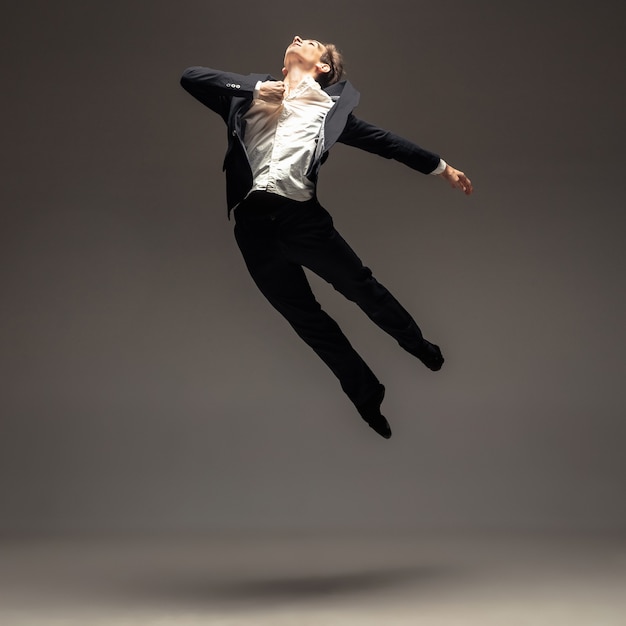 Free photo man in casual office style clothes jumping and dancing isolated on grey