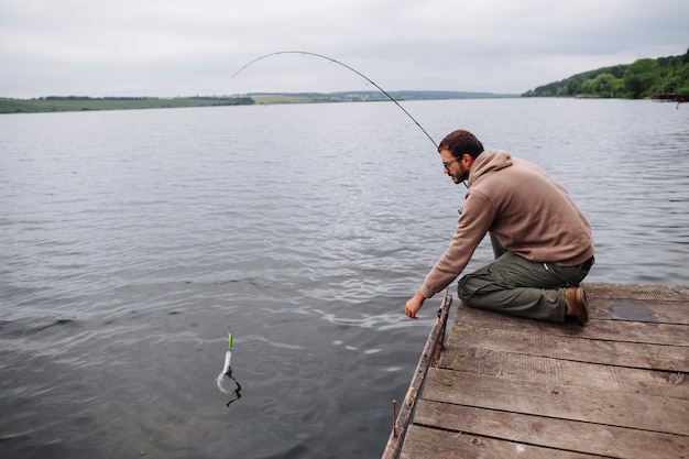 Man catching fish with fishing rod in lake