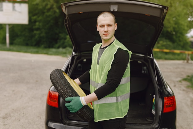 Free photo man changing broken wheel on car