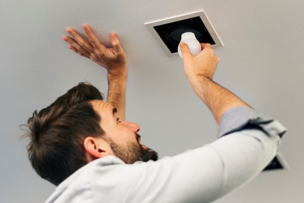 Free photo man changing a light bulb