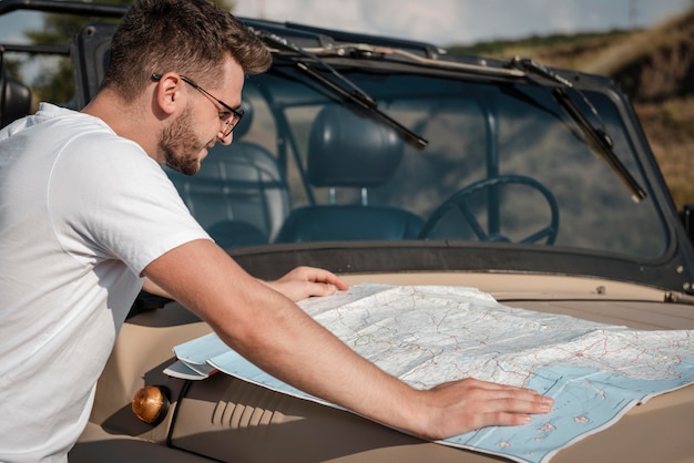 Free photo man checking map while traveling by car